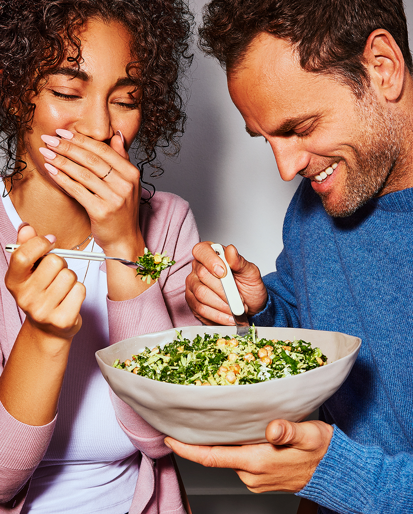 Two people enjoying a bowl zesty kale caesar arte salad together.