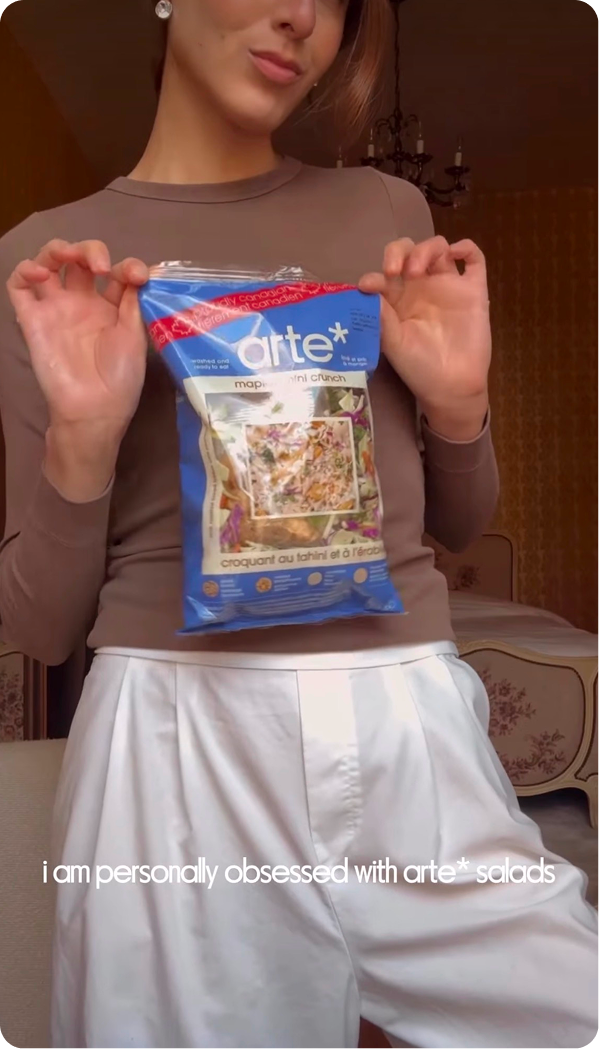 Person holding a blue package of Arte salad in a home setting