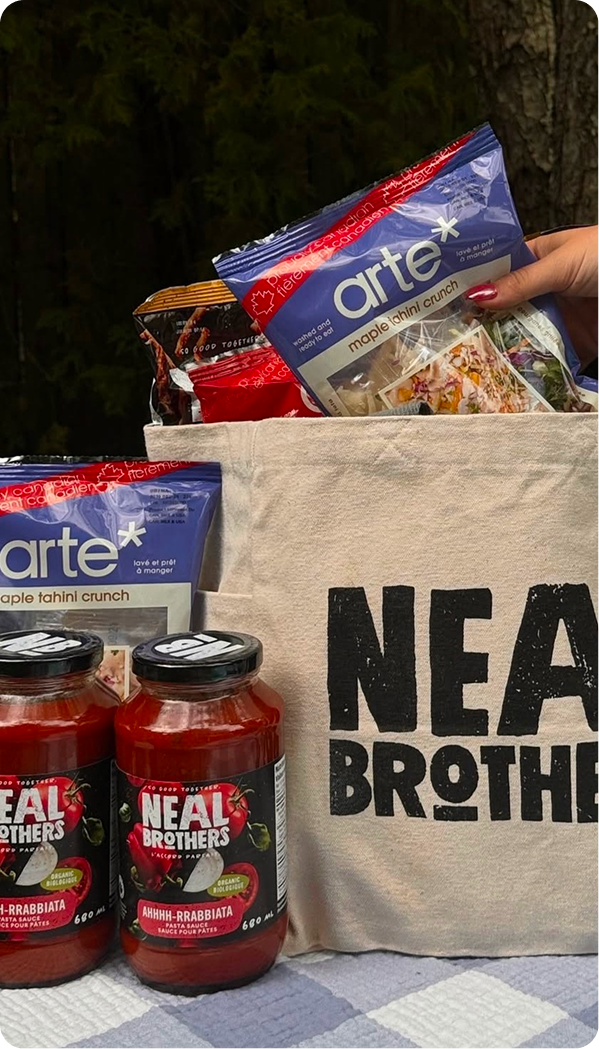 Tote bag with 'NEAL BROTHERS' branding filled with food items including jars and bags.