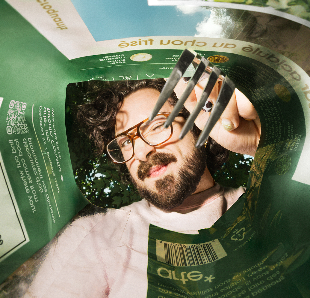Person holding a green package with a fork, looking through it.